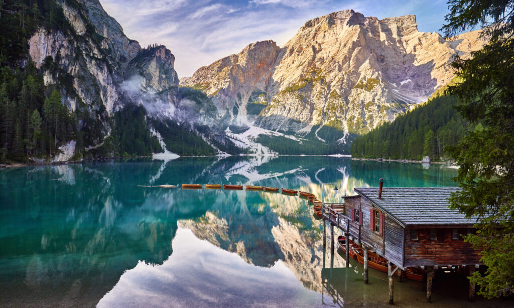 Amazing view of Braies lake at sunrise with little boats