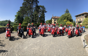 Grosse Gruppe von Leuten auf roten Vespas, bereit für die Abfahrt.