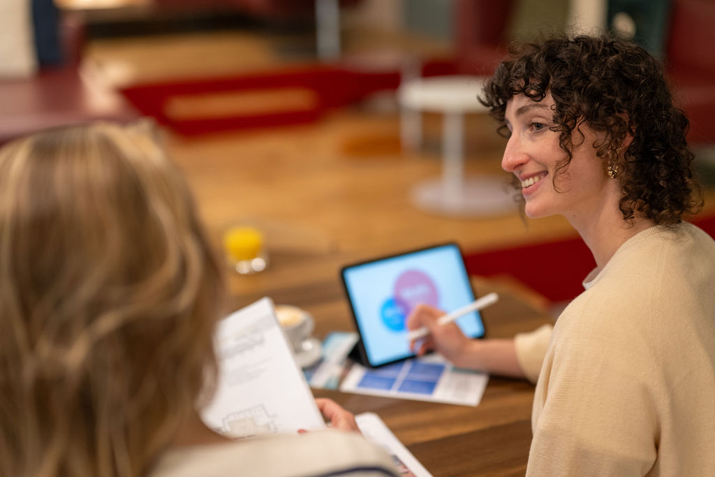 Two event planner are looking at each other, with an Ipad and brochure in hand.