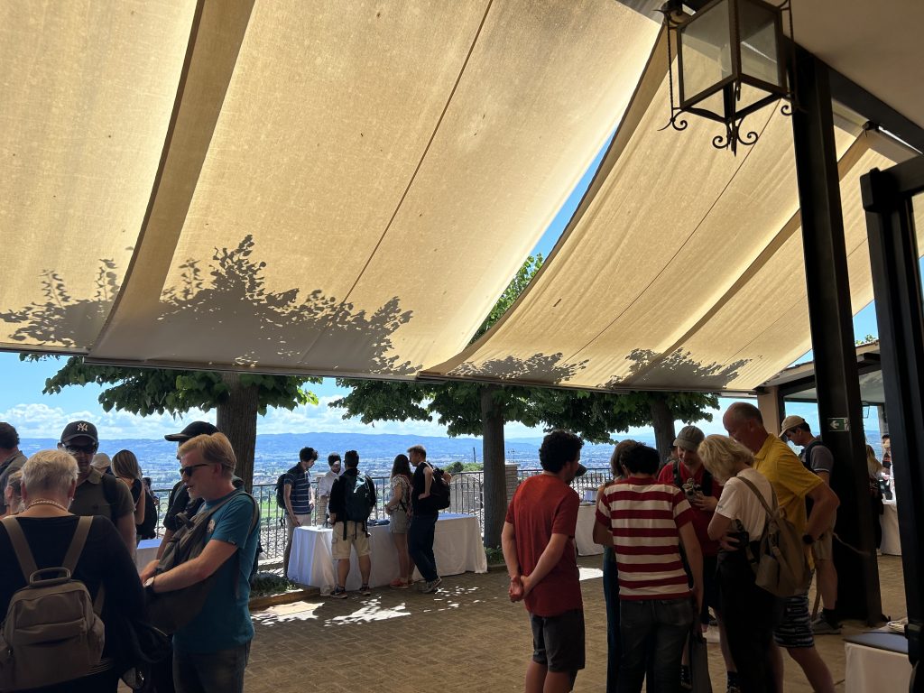 A group of people talking in the shade on a summer day.