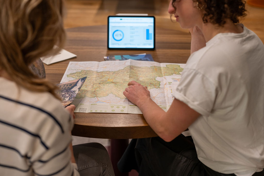 Two people are planning a retreat, map and iPad on the table.