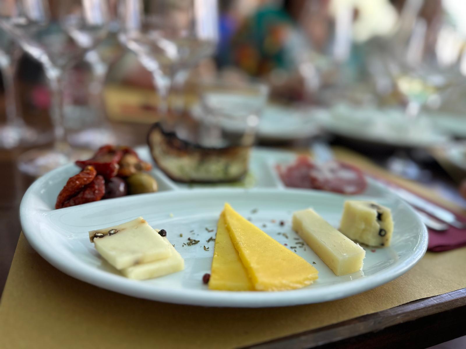 Plate with cheese, dried tomatoes and more food on it. 