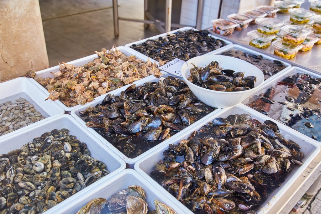 Mussels and seafood on trays with price tags on the street market.