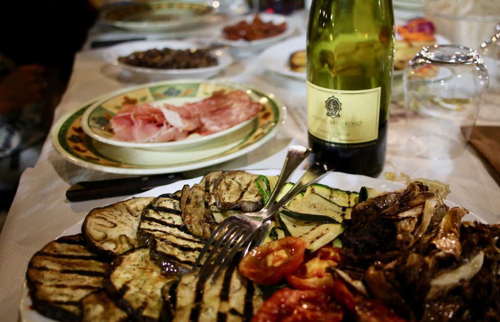 Table full of tuscan specialities and a bottle of wine.