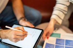 iPad, brochure and two people in a meetnig