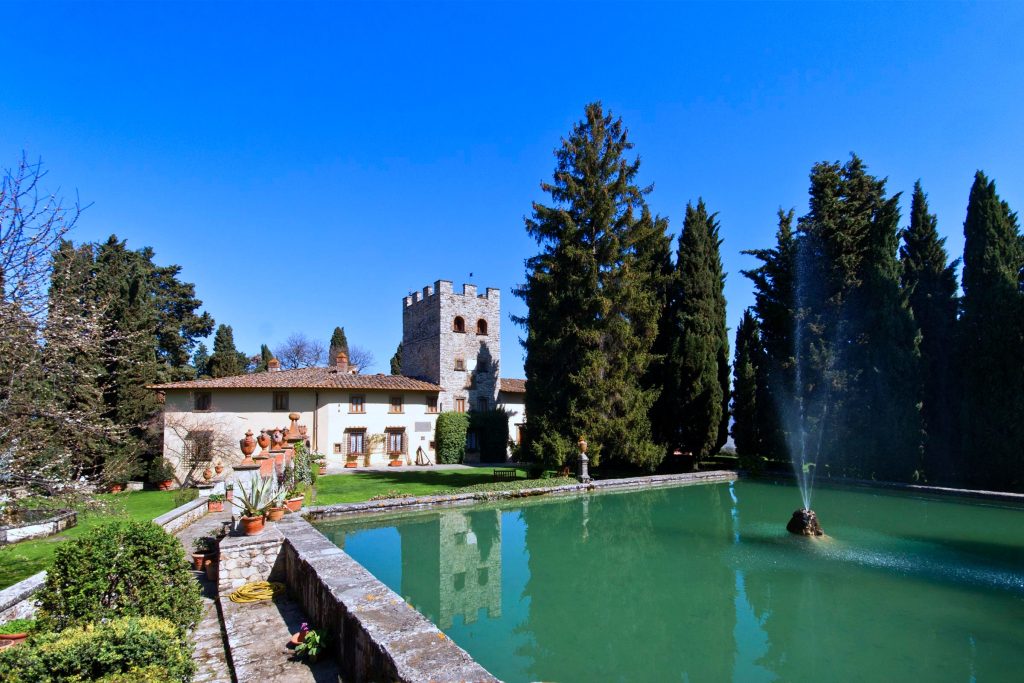 Castello in italy, in the woods with a big pool in front.
