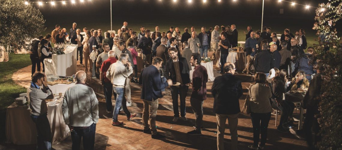 Group of people at a garden party outside at night, lights.
