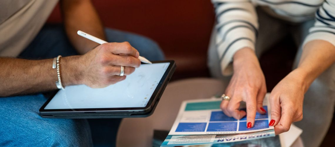 two people planning an en event with iPad and brochure in their hands.