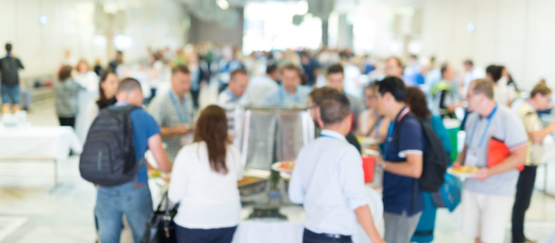 Abstract blurred people socializing during buffet lunch break at business meeting or conference.